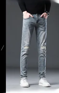 Detail of light blue slim fit jeans featuring knee distress and colorful spray paint dots
