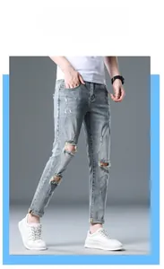 Detailed shot of men's slim fit distressed blue jeans with cuffed hem and selvedge edge