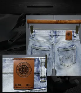 Detailed close-up of brown leather waist label on blue washed denim shorts for men