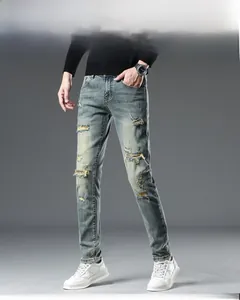 Détails d'un jean bleu pour homme avec effet délavé, déchirures et coupe ajustée