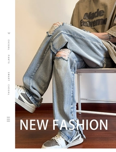 Dettaglio di jeans azzurri strappati con rotture sulle ginocchia e zip laterale sul fondo