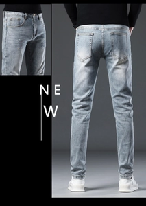 Detail of light blue denim jeans with white wash finish and subtle colored paint splatters
