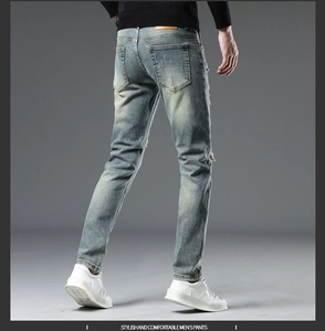 Vue macro d'un jean slim pour homme avec poche arrière usée et étiquette de marque en cuir