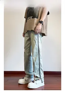 Detail of light blue washed jeans featuring side zippers and distressed ripped knee patterns