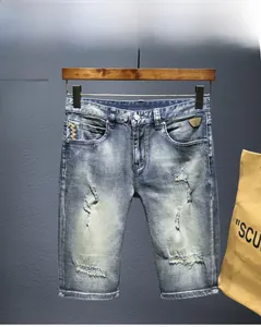 Dettaglio dei pantaloncini di jeans sbiaditi con ricamo a onde ed etichetta in pelle