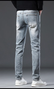 Macro view of light blue slim fit jeans featuring back pockets and washed denim texture