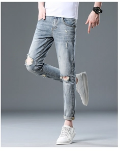 Detail of distressed ripped jeans featuring slim fit cut and stylish frayed denim textures