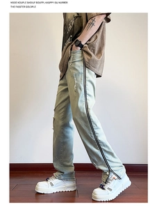 Detail of light blue vintage straight jeans featuring side zippers and distressed holes