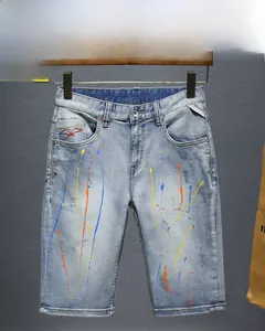 Macro view of light blue denim shorts with colorful paint splatter and distressed details