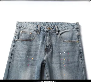 Detail view of denim waist with metal button, pockets and colorful paint splatters