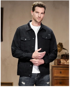 Detailed close-up of a men's black denim jacket with classic flap pockets and button closure