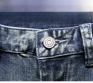 Vista macro del bottone in metallo e della fascia cucita sui pantaloncini di denim