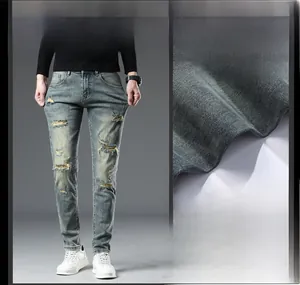 Détail du tissu denim élastique montrant le genou déchiré et la texture délavée bleue