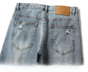 Detail of light blue ripped jeans showing leather brand tag and distressed back pocket