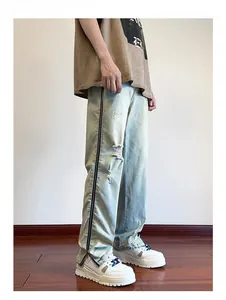 Detail view of light blue distressed jeans with full-length metal zipper and knee rips