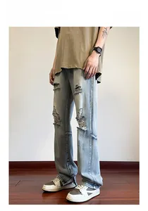 Dettaglio di jeans azzurri strappati con finiture usurate e cerniere metalliche laterali