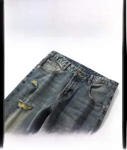 Détails du jean bleu-gris avec déchirures usées, trous et bouton métallique frontal