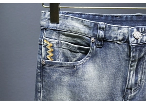 Dettaglio degli shorts in denim con lavaggio vintage e ricamo a zig-zag sulla tasca