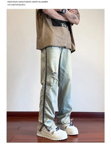 Detail of vintage blue straight jeans with distressed ripped holes and side zipper metal trim