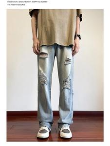 Dettaglio dei jeans azzurri da uomo con strappi sulle ginocchia e texture vintage denim