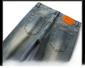 Détail de jean bleu délavé avec écusson en cuir orange et poches à double surpiqûre