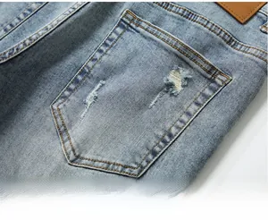 Detail of light blue distressed denim back pocket with vintage leather brand patch