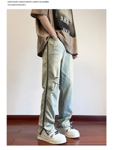 Detail view of light blue distressed jeans with side zipper accents and relaxed fit
