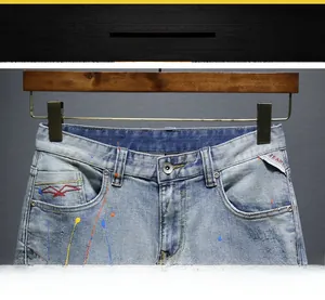 Detail of denim shorts with colorful paint splatters and red bird embroidery logo
