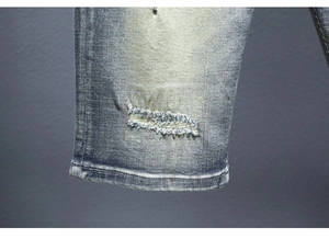 Dettaglio di pantaloncini in denim azzurro con cuciture arcobaleno e bordi invecchiati