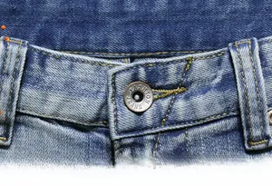Detail shot of the metal button and denim texture on vintage distressed shorts