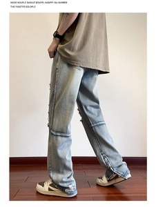 Dettaglio dei jeans azzurri con strappi sulle ginocchia e spacchi laterali con zip sul fondo
