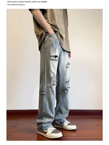 Dettaglio dei jeans azzurri da uomo con cerniera metallica laterale e strappo sul ginocchio