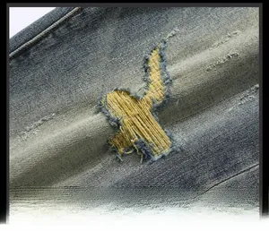 Détails macro du denim gris-bleu avec coutures jaunes renforcées et effet déchiré mode