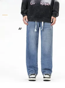 Détail d'un jean baggy délavé bleu clair avec cordon de serrage et coupe jambe droite