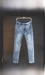 Detailed macro view of light blue washed denim jeans with metal button and waist label