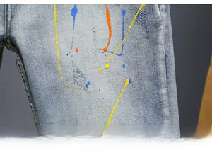 Macro detail of vintage denim shorts featuring colorful paint splatter and washed fabric