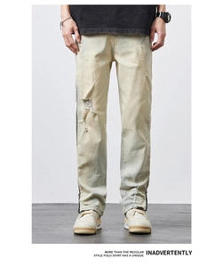 Detail view of vintage yellow washed jeans featuring distressed holes and ankle zippers