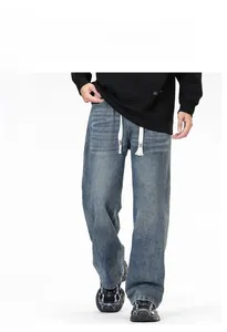Détail d'un jean délavé vintage pour homme avec une coupe large et un cordon à la taille