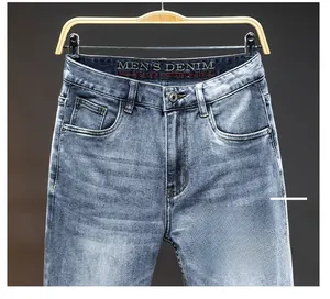 Detail view of men's slim fit jeans with light blue wash and metal button accents