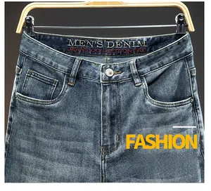 Detailed close-up of men's blue washed denim waist featuring metallic button and inner branding