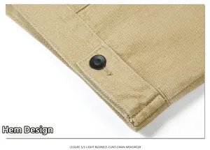 Close-up of khaki cotton twill jacket hem featuring precision stitching and a black button