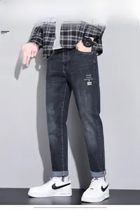 Detail view of dark blue slim fit jeans with graphic print and stylish cuffed hem