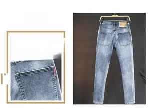 Close-up of light blue washed denim jeans with a red woven tag and brown leather waist patch