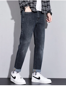 Detail view of dark blue washed slim-fit jeans featuring whiskering and faded textures