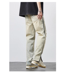 Detail view of light wash denim jeans featuring side zipper design and distressed hem texture