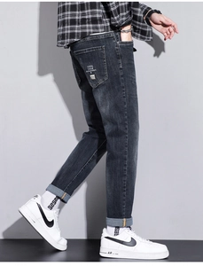 Detail of slim fit dark grey denim jeans featuring a unique rear pocket graphic print
