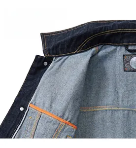Detailed interior of dark blue denim jacket with orange stitching and inside pocket