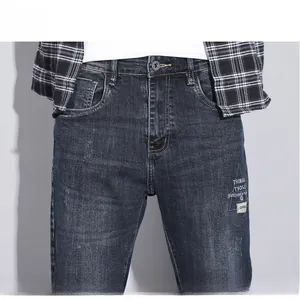 Detailed macro view of dark blue men's slim fit jeans with embroidery and whiskering