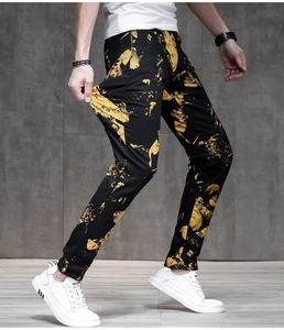 Dettaglio di jeans slim neri con stampe astratte gialle effetto schizzi di vernice