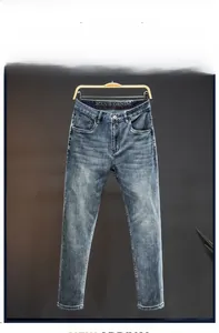 Detail of men's slim fit straight leg jeans featuring cat whisker wash and denim texture